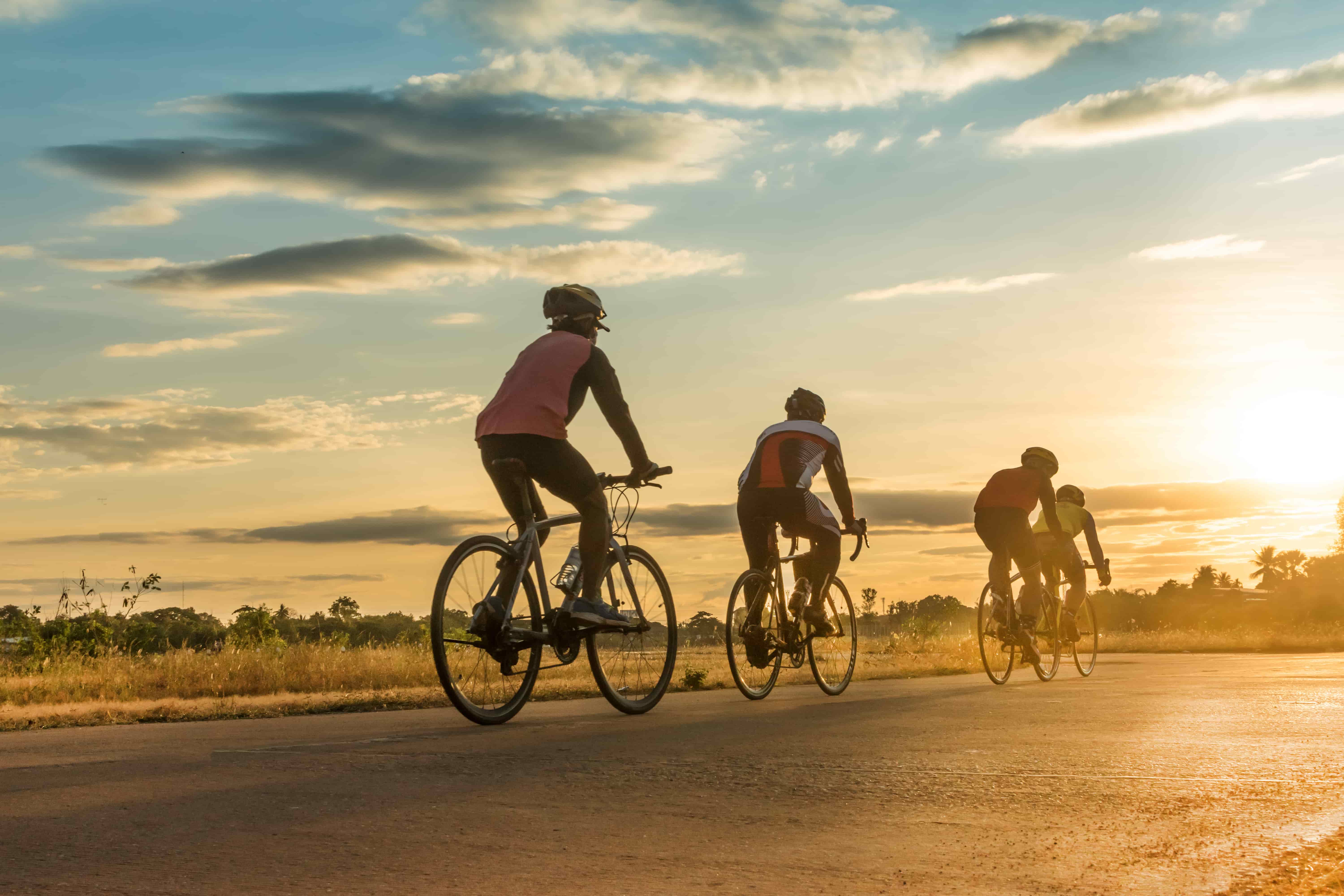 Bike riders cycling on trail towards sunrise